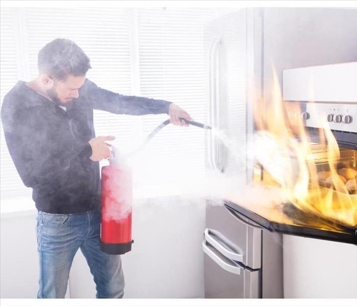 Man with a fire extinguisher pointing at an oven